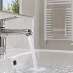 Miscelatore del lavabo con un getto d’acqua e radiatore sullo sfondo di un bagno luminoso